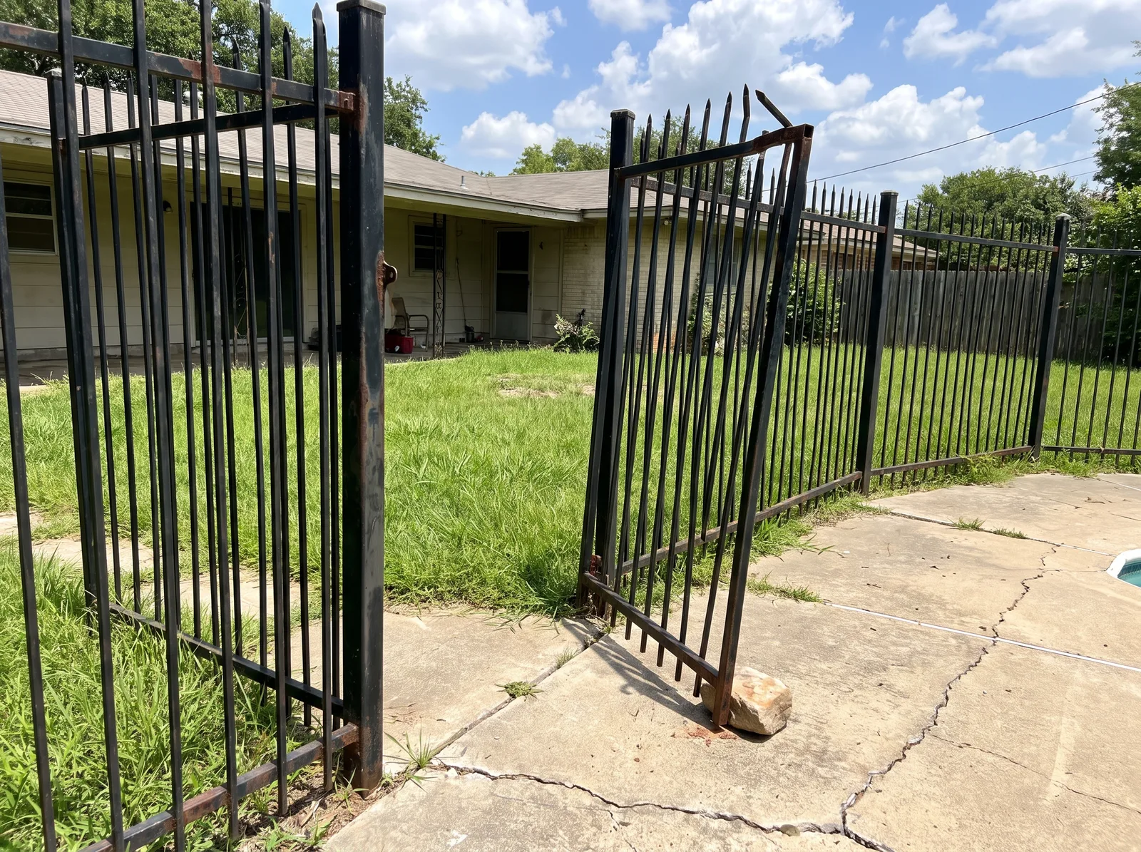 Pool fence gate hanging crooked off a failed top hinge and dragging on the pool deck instead of latching shut