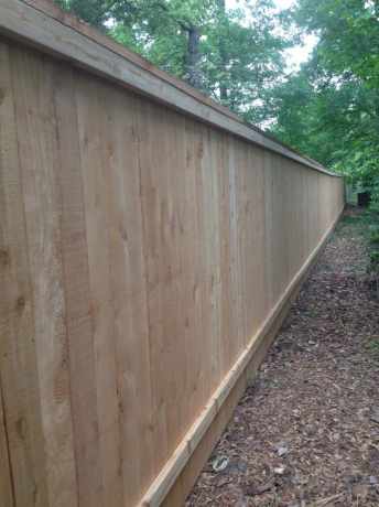 Tall wood privacy fence along a wooded back property line