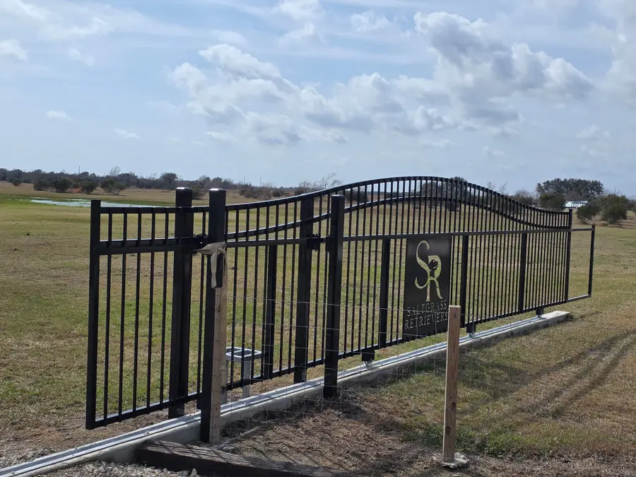 Aluminum fencing and an arched double entry gate on open acreage