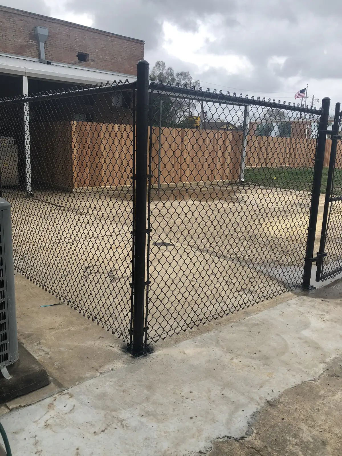 Black chain link fence and gate across a concrete drive