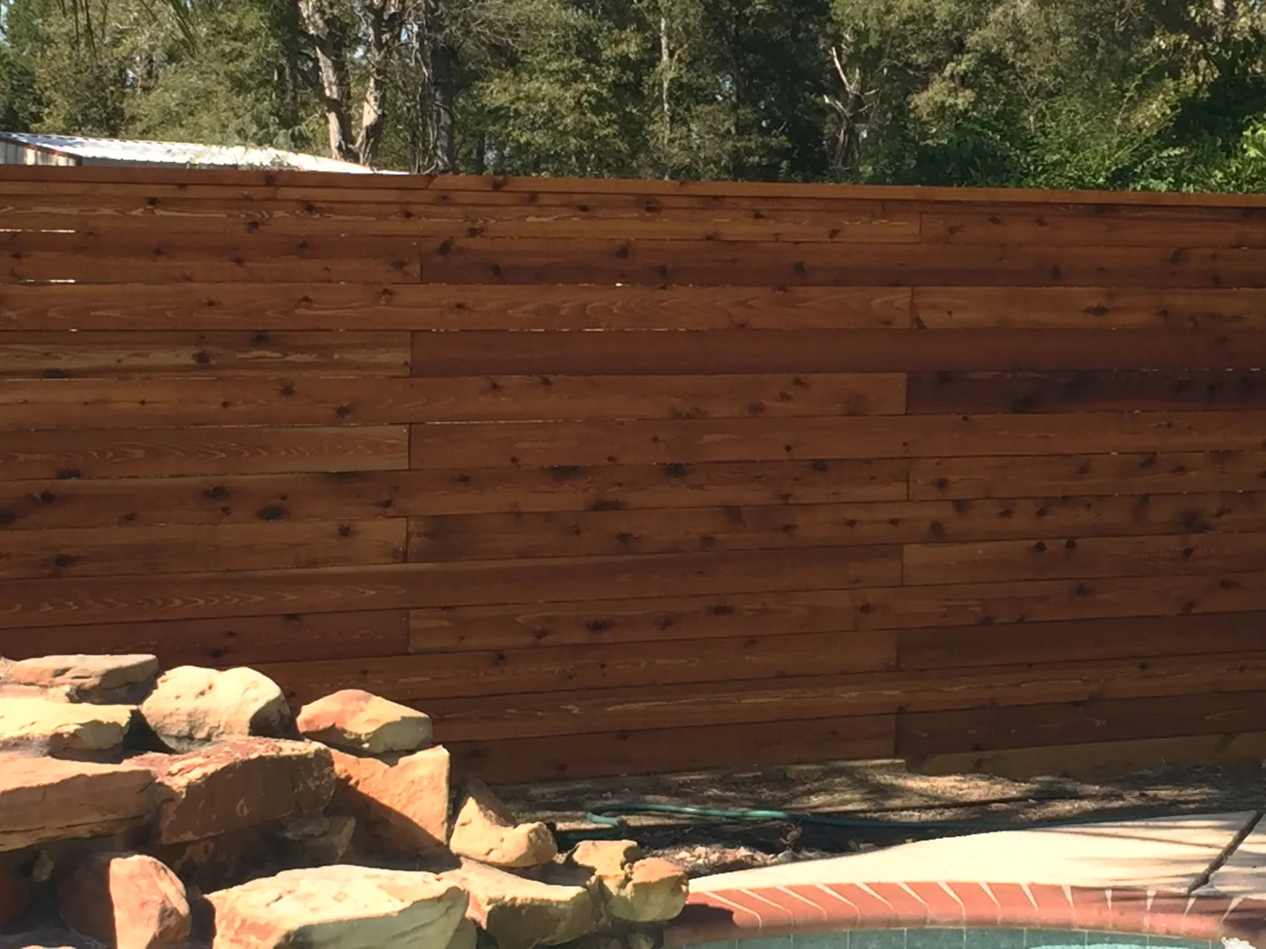 Horizontal wood fence boards above a stone waterfall