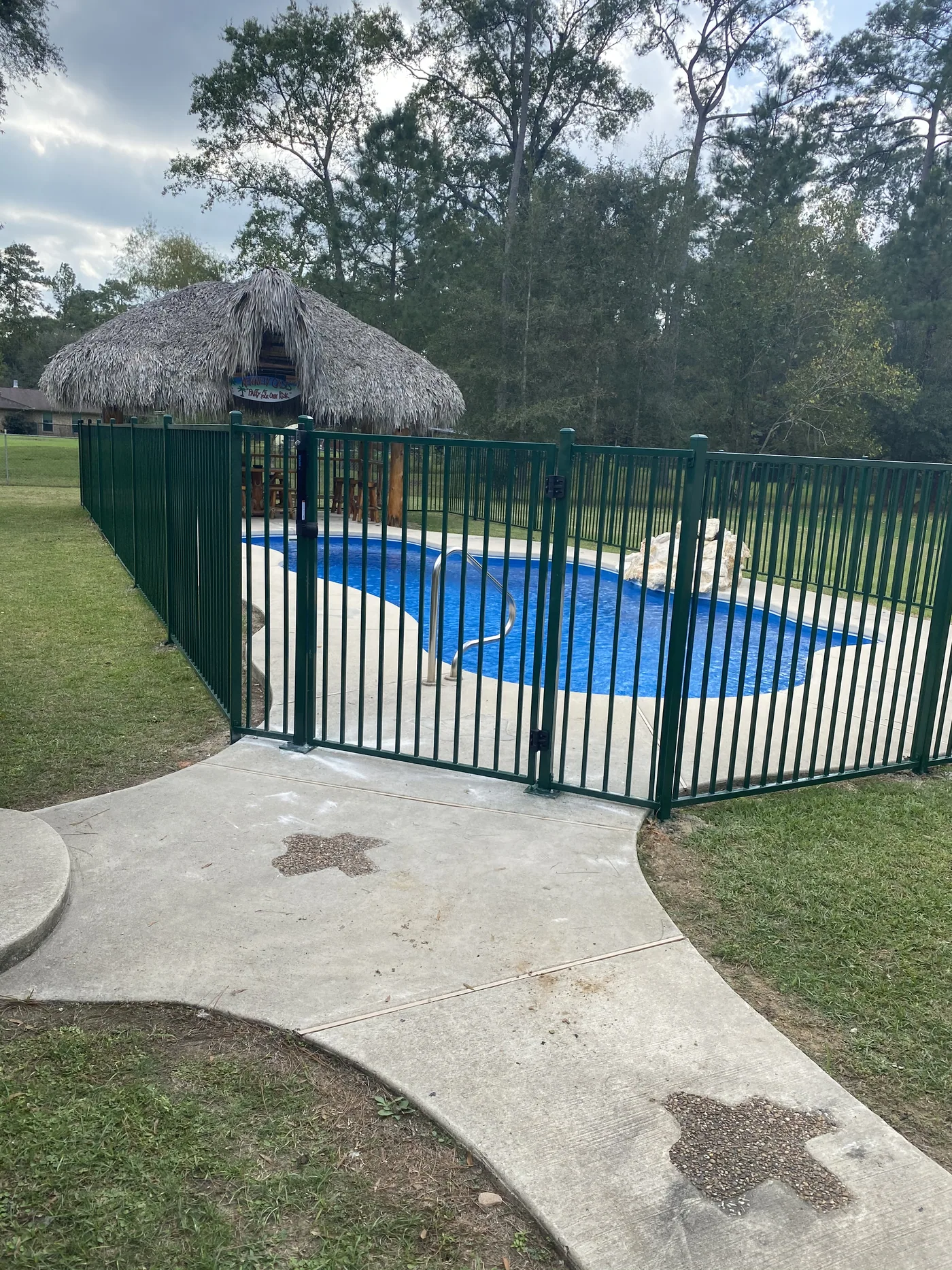 Pool safety fence with a self-latching gate enclosing a backyard pool