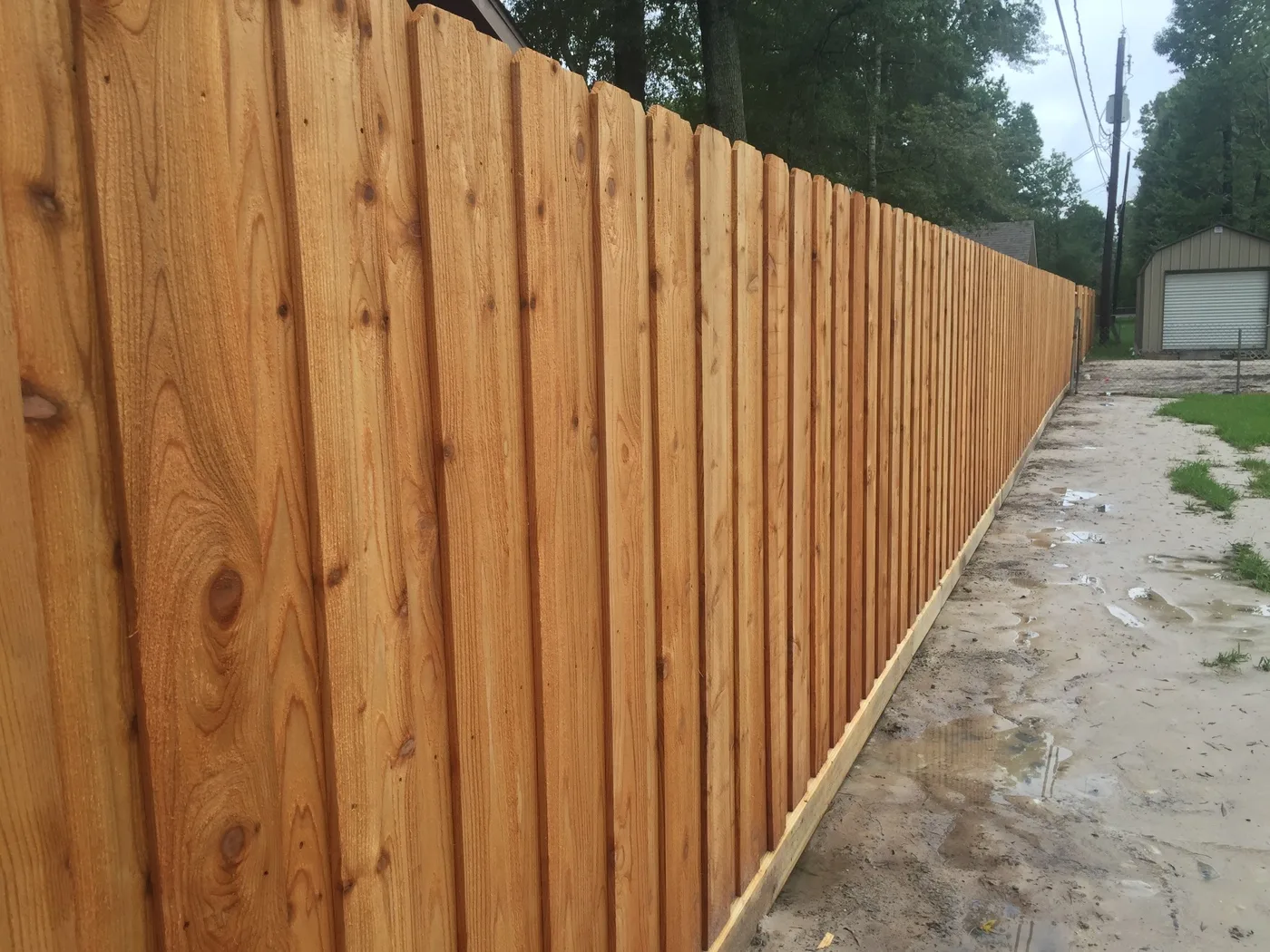 Wood privacy fence built in cedar, running along a driveway