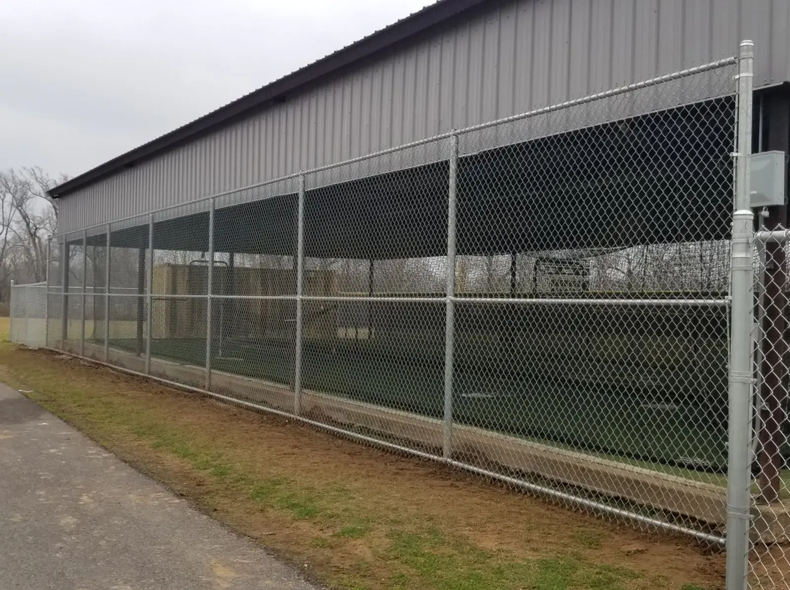 Tall galvanized chain link commercial fence along a property line