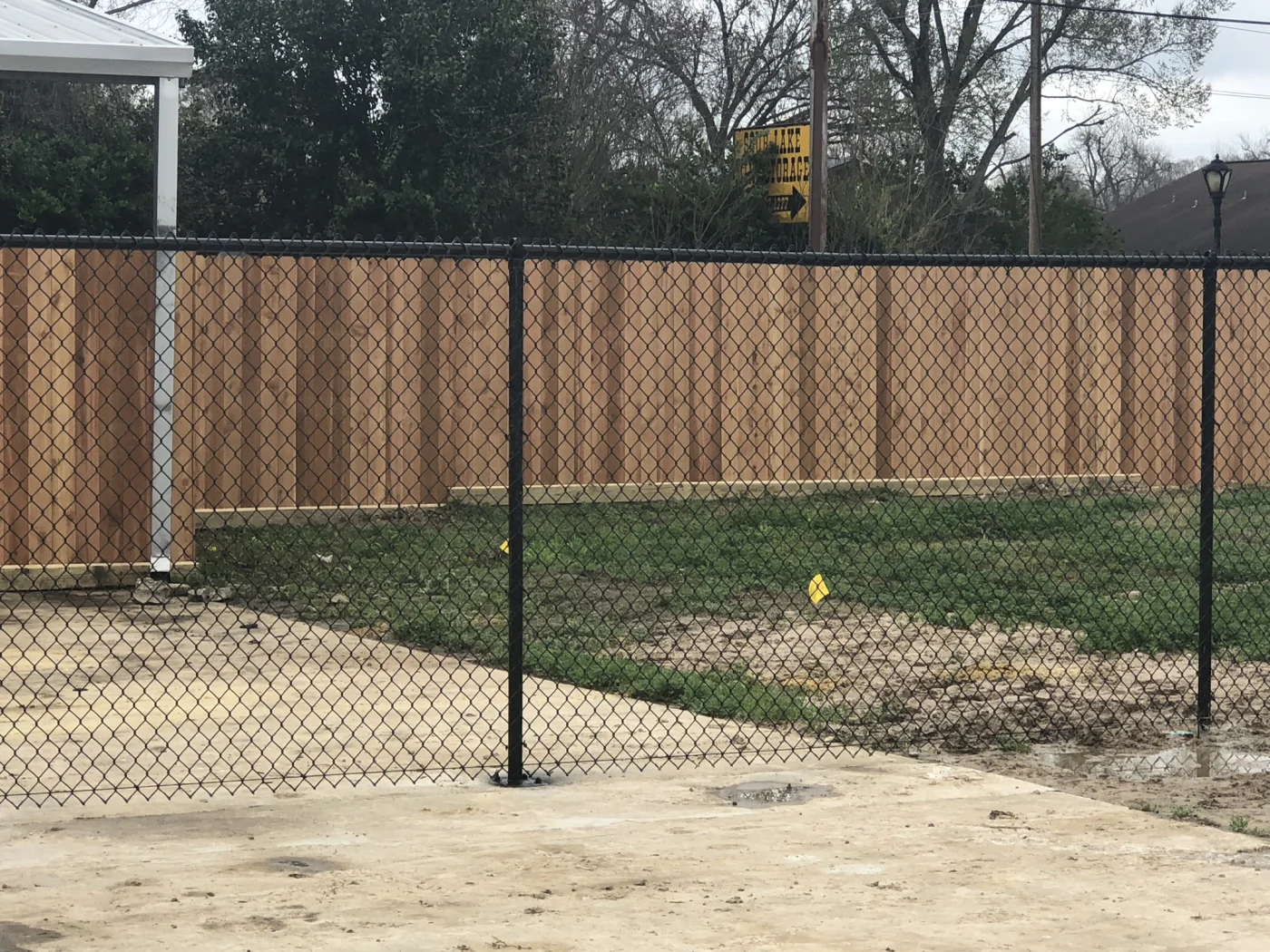 Black chain link fence in vinyl coating along a concrete pad