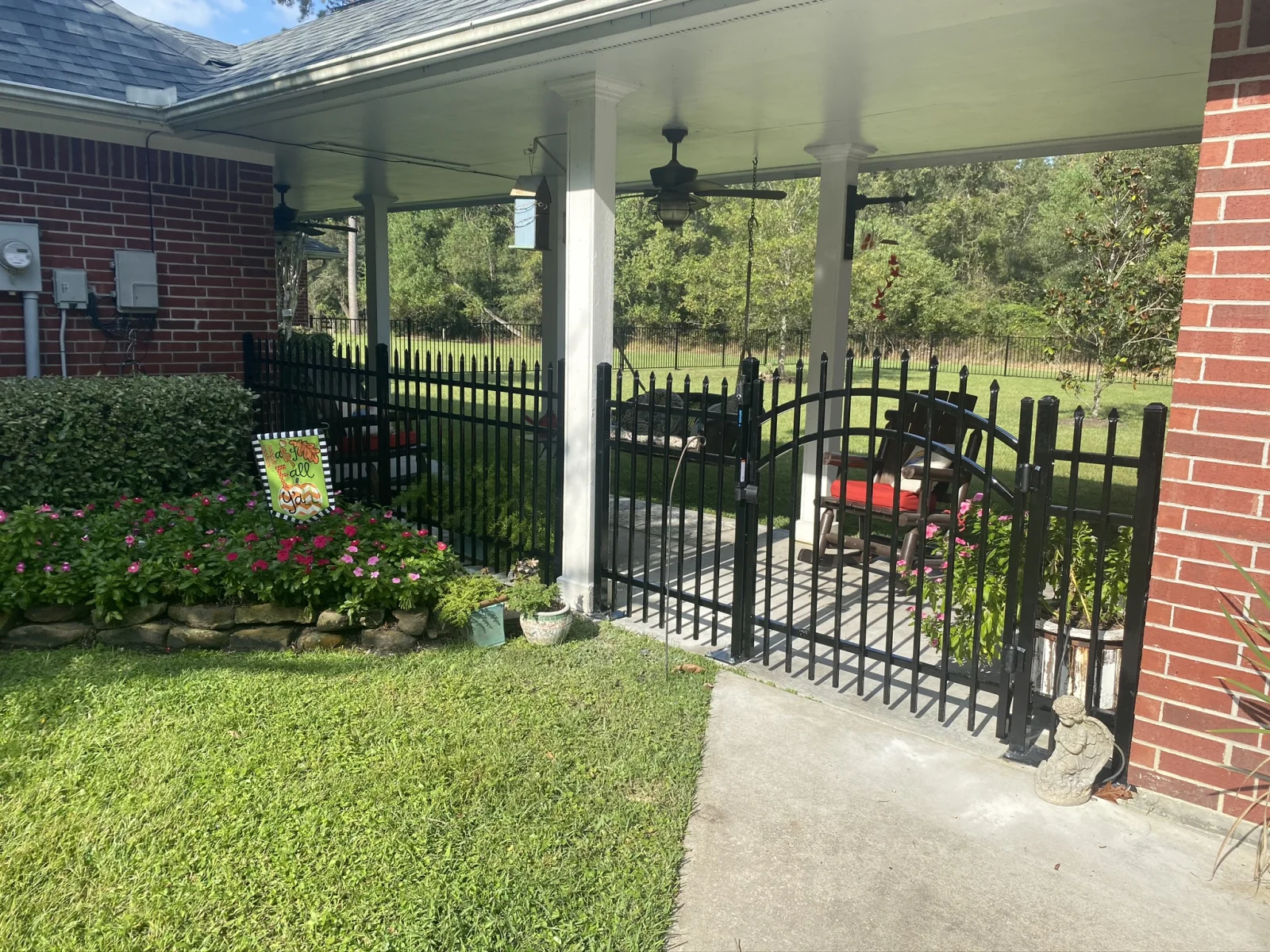 Black aluminum fence with an arched gate beside a covered patio
