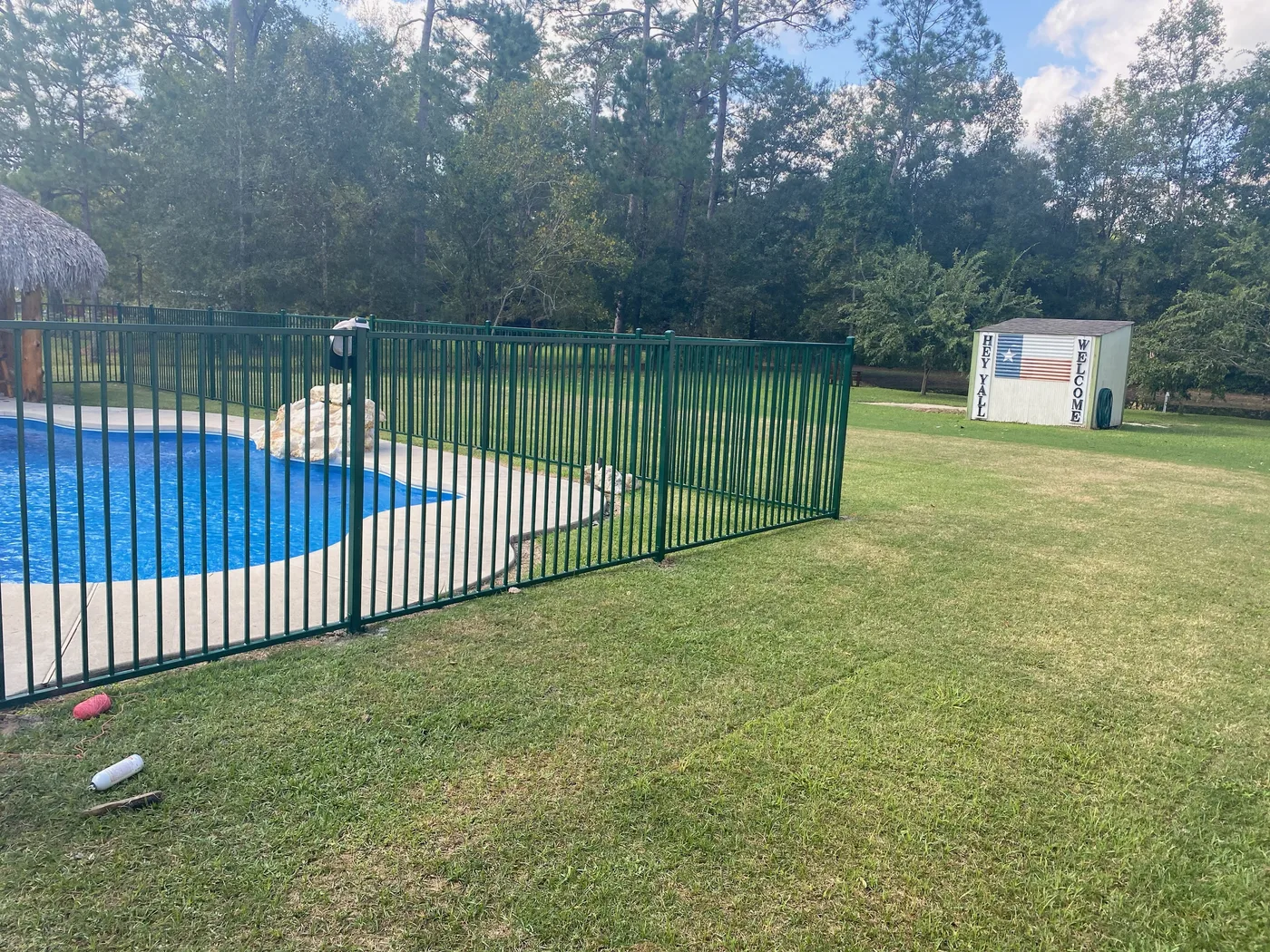 Green powder-coated aluminum pool fence enclosing a backyard pool