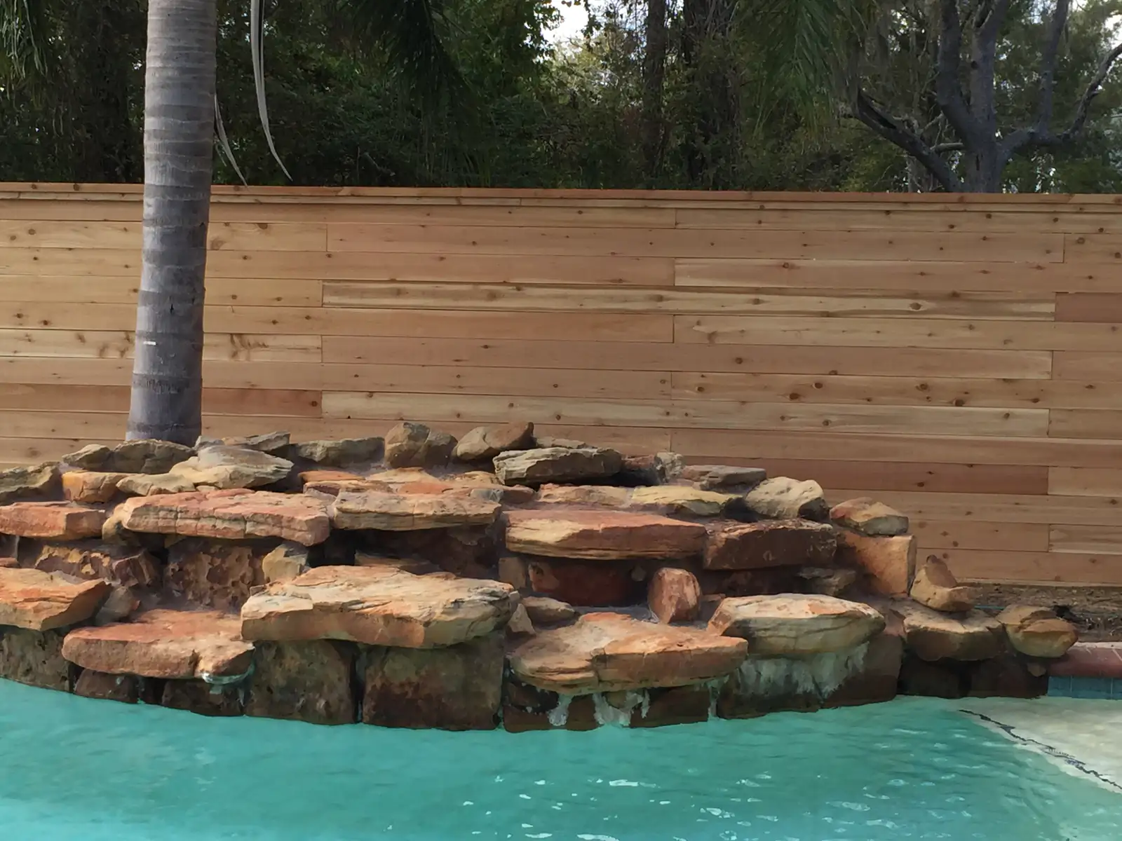 Backyard pool enclosed by a horizontal wood privacy fence
